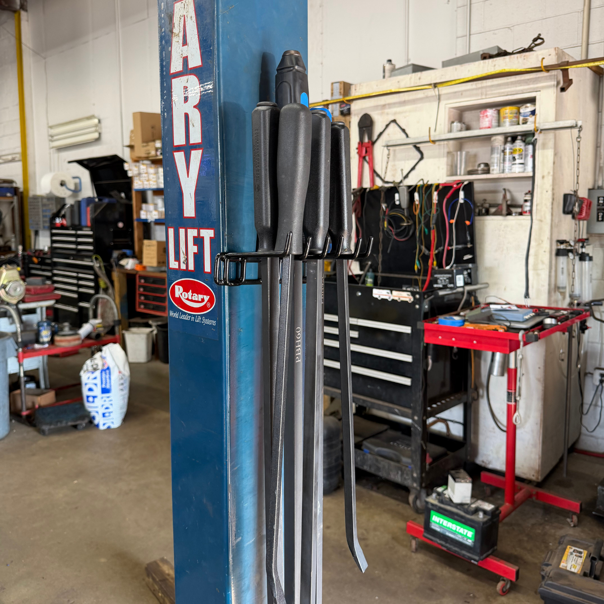 Pry Bar magnetic hook holding six pry bars on a blue steel vehicle lift.